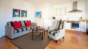 A living room with a sofa, armchair, coffee table, and artwork on the wall. - Barbarossa Whg B-08. - B-08 (Kühlungsborn)
