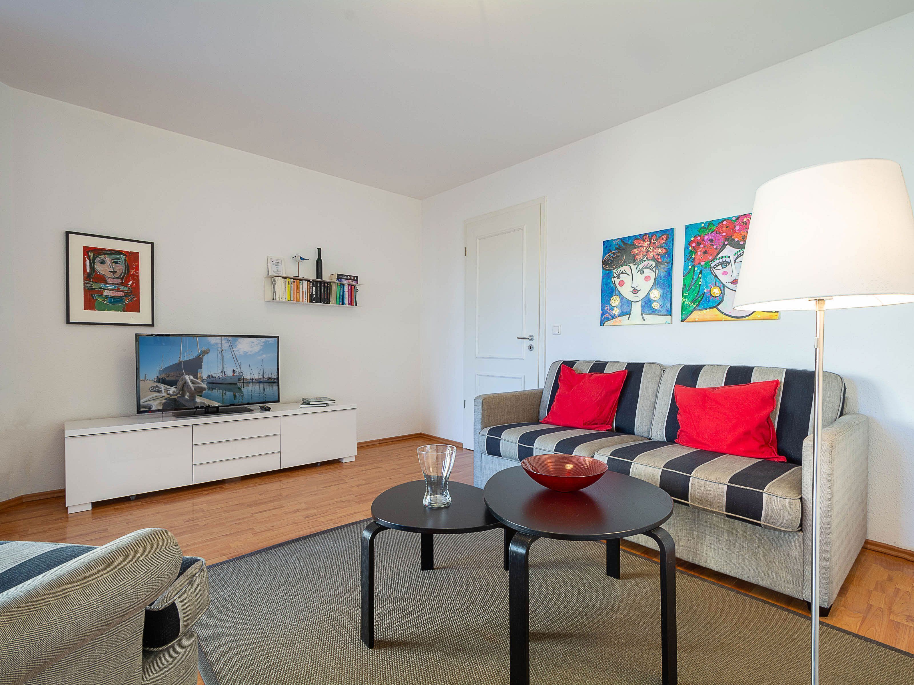 A modern living room with a sofa, a coffee table, a TV, and artwork on the walls.