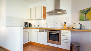 A modern kitchen with white cabinets, stainless steel appliances, and a tiled backsplash. - Barbarossa Whg B-08. - B-08 (Kühlungsborn)