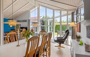 A spacious room with large windows, a dining area with wooden chairs, and a modern chair. - Cozy home in Sydals with sauna (Sydals)