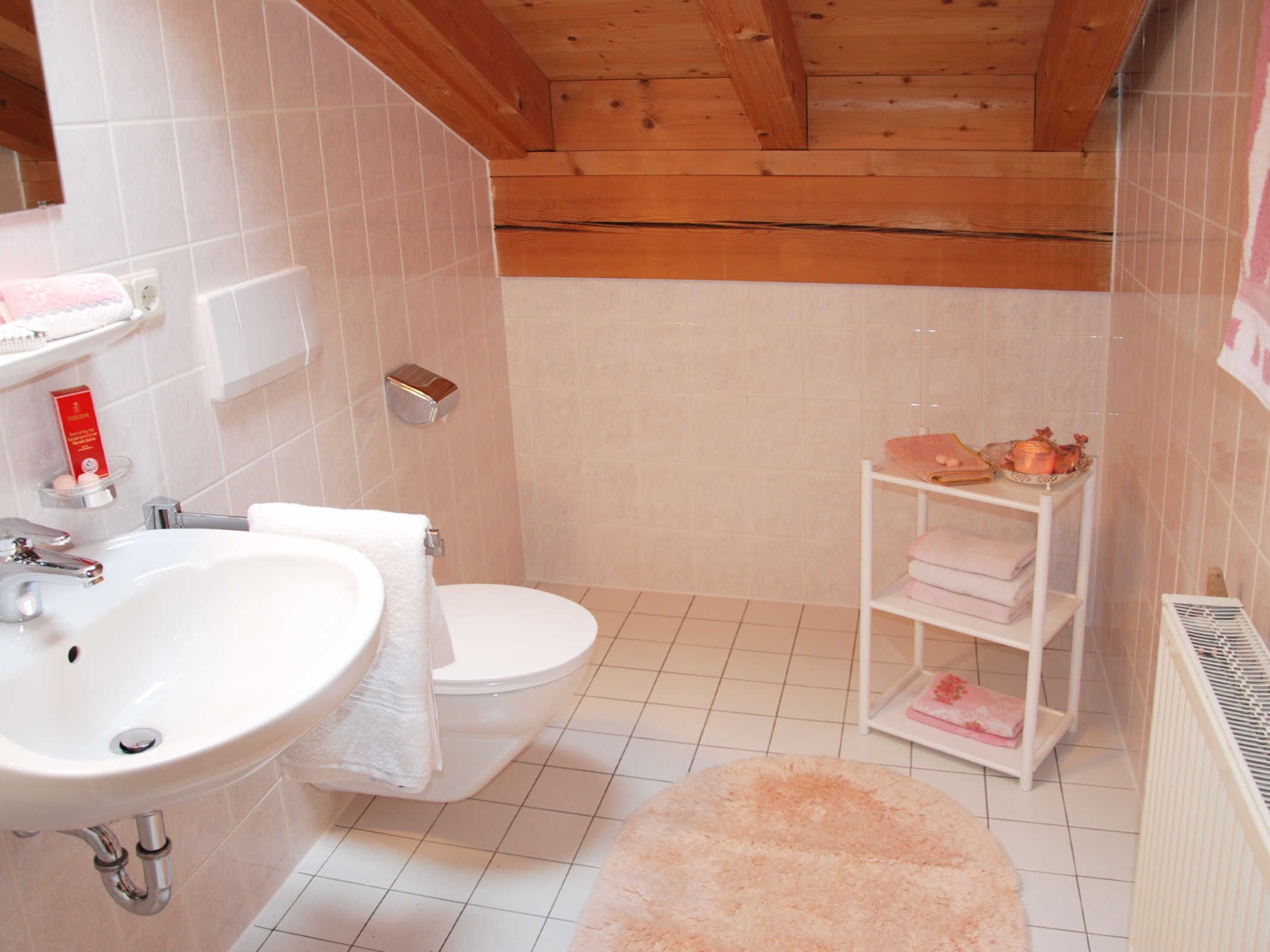 Un baño con lavamanos, inodoro y estante con toallas.