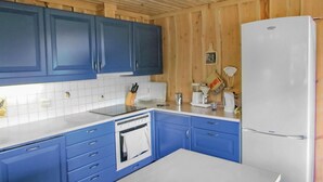 Une cuisine avec des meubles bleus, un réfrigérateur blanc et un dosseret carrelé.