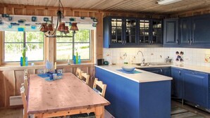 Une cuisine avec une table en bois et des placards bleus.