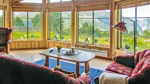 Une pièce chaleureuse avec de grandes fenêtres, une table décorée de bougies et une vue sur un paysage montagneux.