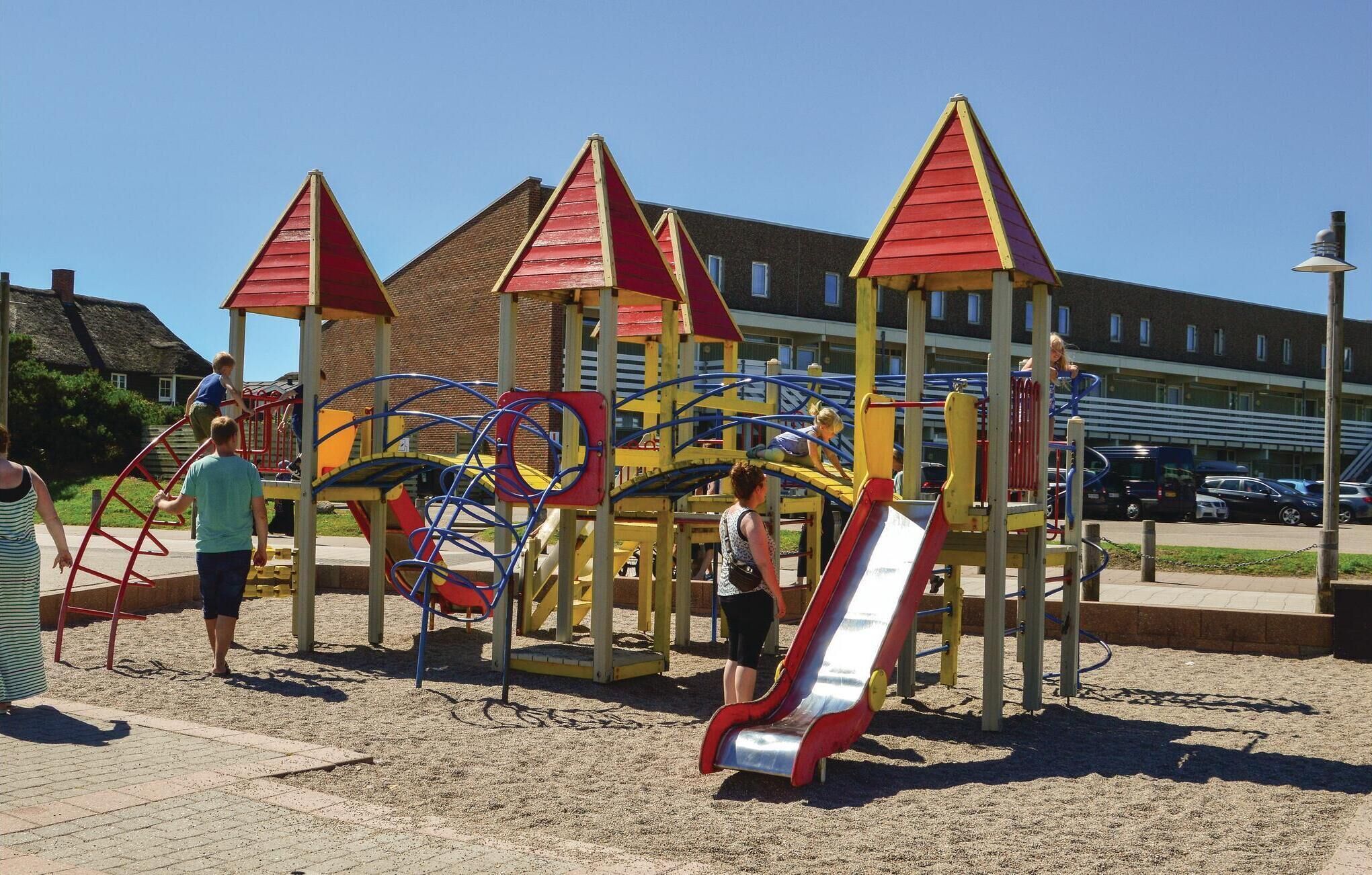 Un parque infantil con estructuras para escalar, toboganes y suelo de arena.