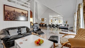 A spacious living area with a sofa, coffee table, and a dining table with chairs. A cityscape painting is on the wall, and there is a foosball table in the dining area. - Lovely home in Ringkøbing with sauna (Ringkøbing)