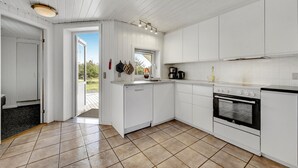 A modern kitchen with white cabinetry, a built-in oven, and a window providing natural light. - Lovely home in Ringkøbing with sauna (Ringkøbing)