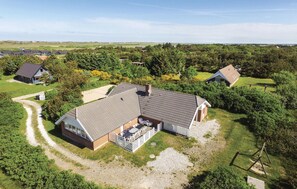 A large house with a spacious patio area, surrounded by a rural landscape.