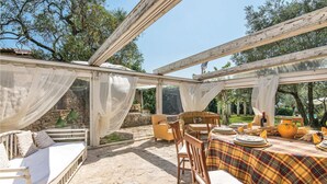 Un área de comedor al aire libre con una mesa dispuesta para cuatro personas, rodeada de sillas y un banco.
