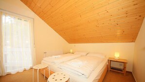 Ein Schlafzimmer mit zwei Betten, einem kleinen Tisch und einem Nachttisch mit Lampe.