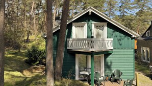 Eine grüne Holzhütte mit Balkon, Tisch und zwei Stühlen.