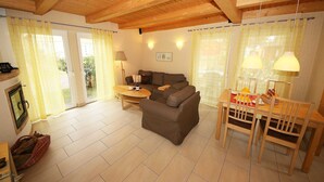 Ein gemütliches Wohnzimmer mit einer Couch, einem Esstisch mit Stühlen und einem Kamin.
