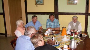 A group of people seated around a wooden table with a cake, glasses, and various dishes. - Apartment 2/ 2-room (45m²; 1-2 pers.) - Country vacation near Ostseebad Rerik (Biendorf)