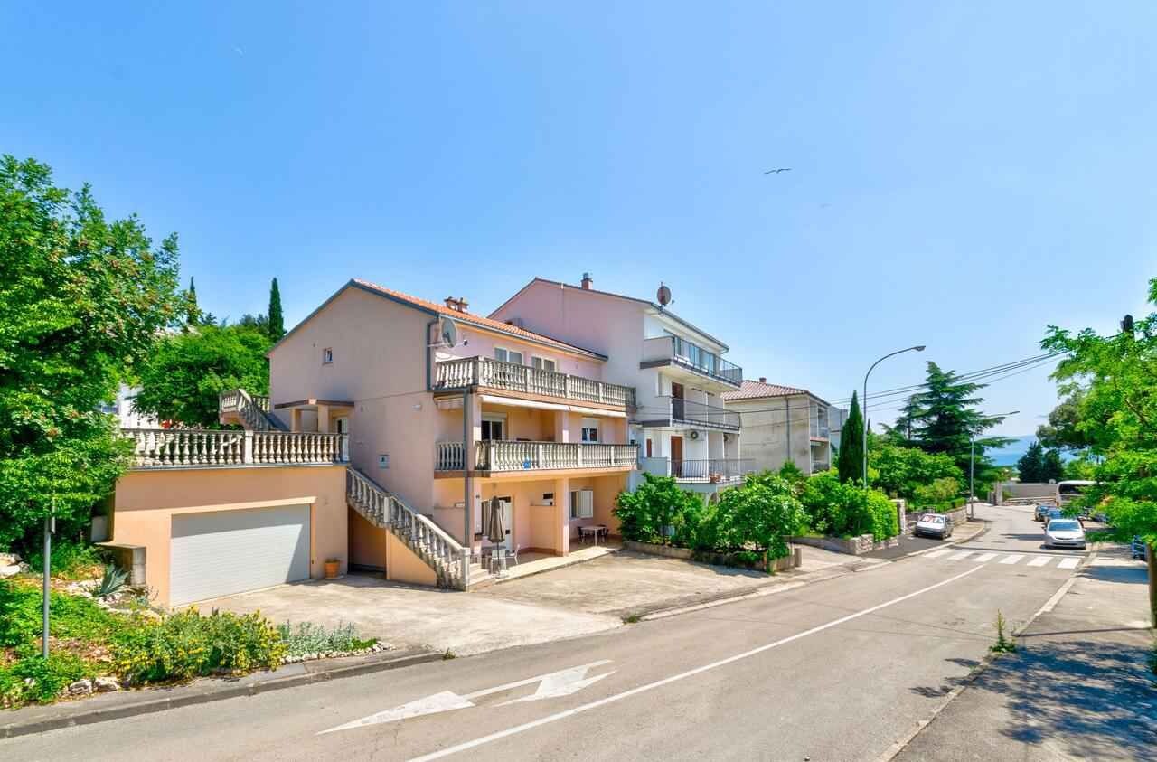 Eine Wohnstraße mit zweigeschossigen Häusern, einer Garage und einem wolkenlosen Himmel.