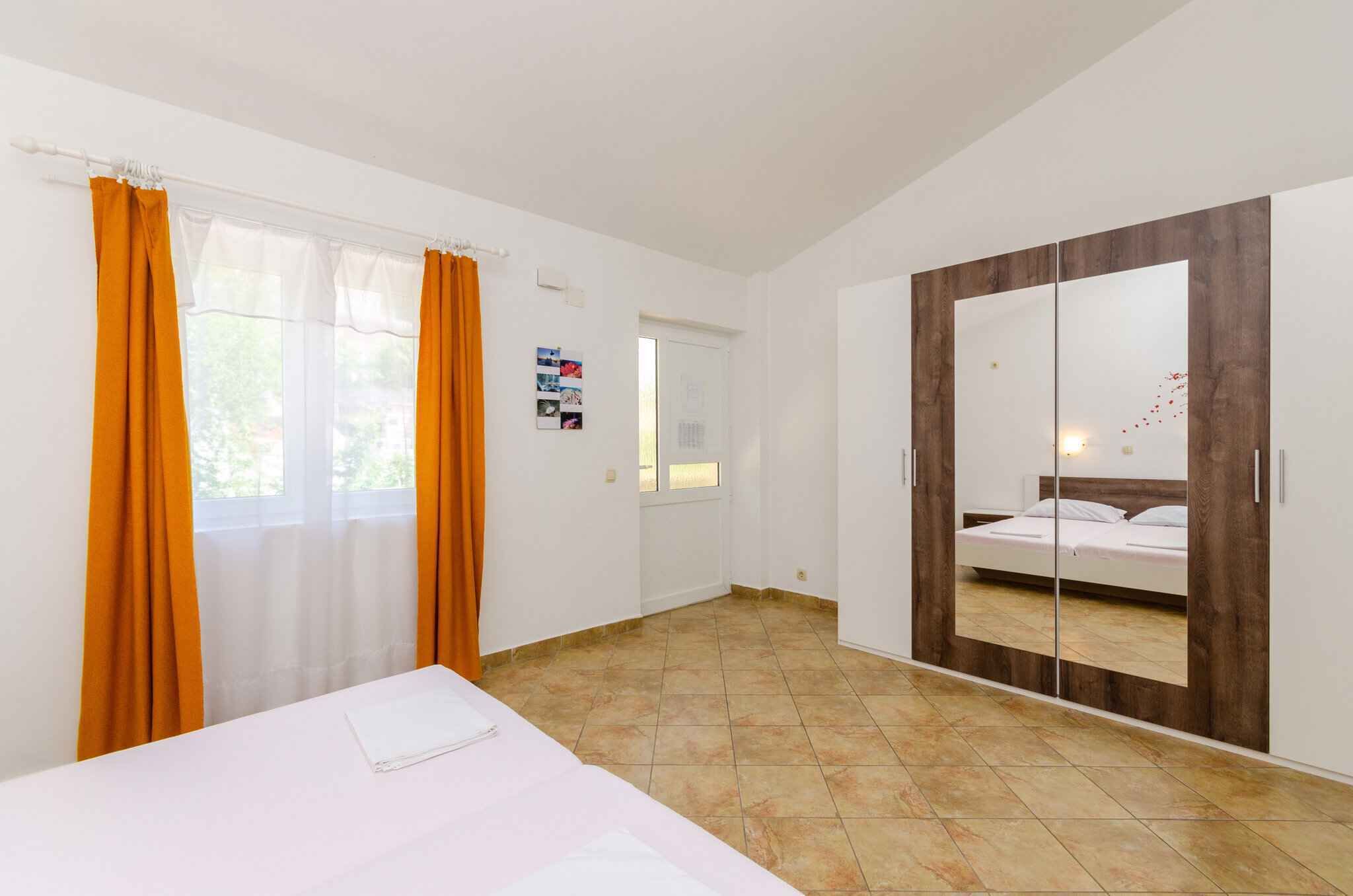 Een slaapkamer met een bed, een kledingkast en een raam met gordijnen.