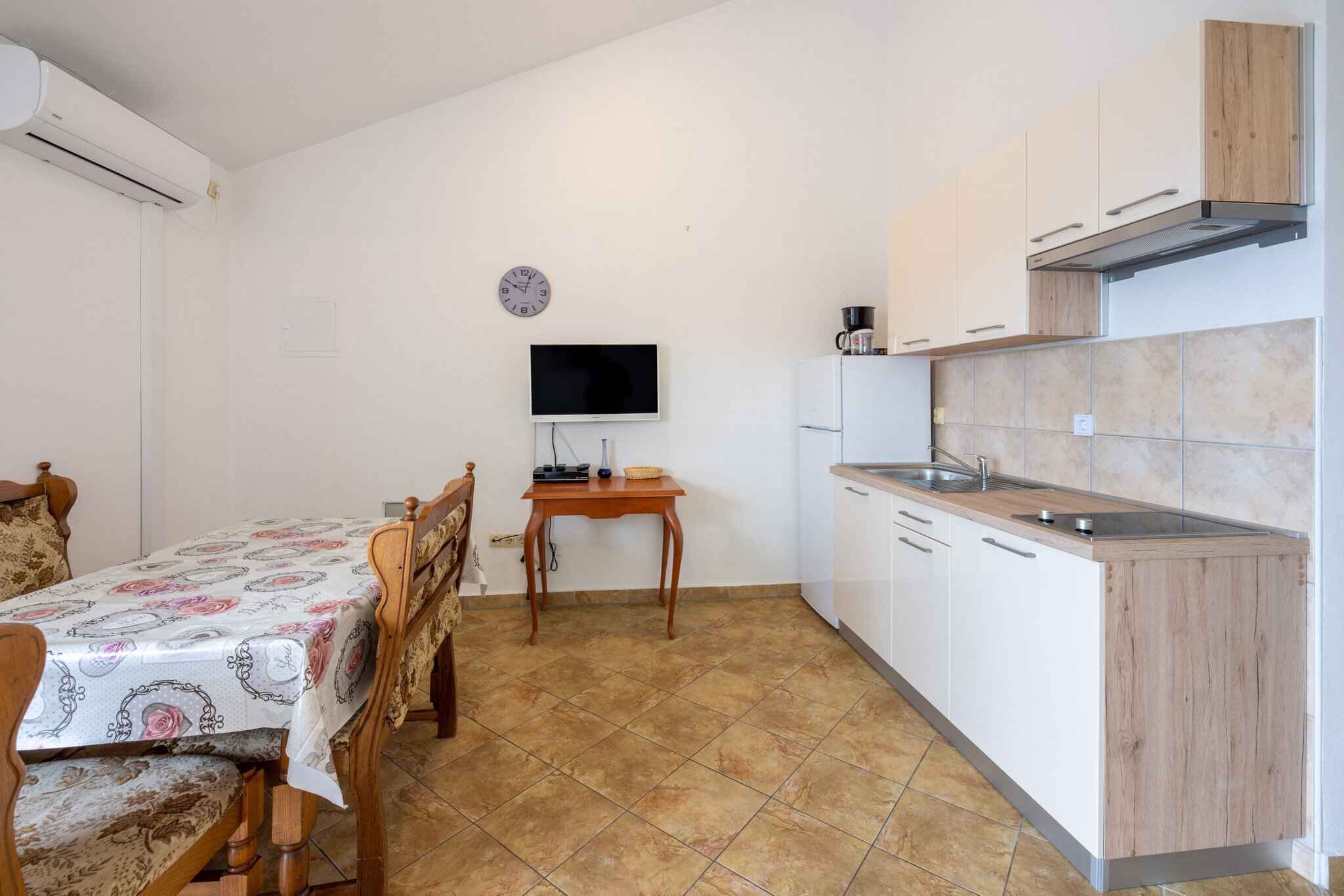 Een kleine keuken met witte kastjes, een houten aanrecht en een betegelde spatwand.