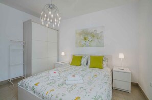 A bedroom with a bed, nightstands, a wardrobe, and a hanging light fixture.