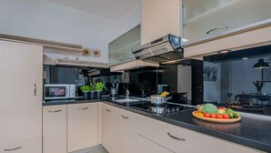 Una cocina moderna con armarios de colores claros, encimera negra y electrodomésticos de acero inoxidable.