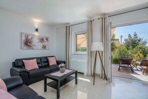 A modern living room with a black leather sofa, a coffee table with a vase of flowers, and a painting on the wall.