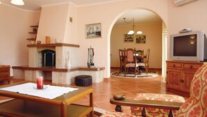 A living room with a fireplace, a television, and a dining area with chairs and a table.