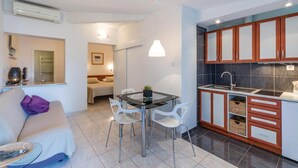 A modern kitchen with a dining area, including a glass table and white chairs. - Pet friendly apartment in Pula with WiFi (Pula)
