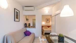A compact living space with a sofa, a glass dining table, a small kitchen area, and a bedroom visible through an open door. - Pet friendly apartment in Pula with WiFi (Pula)