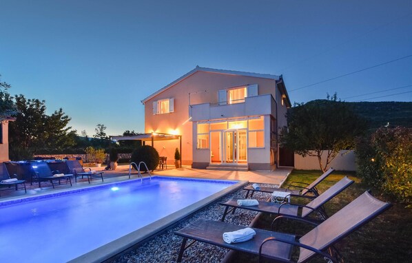A modern two-story house with a swimming pool, outdoor seating, and a well-lit entrance. - Stunning home in Prugovo (Prugovo)
