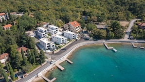 An aerial view of a coastal area with modern buildings, a marina, and a road leading to the water. - Beach front apartment in Omisalj with WiFi (Omisalj)