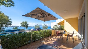 A balcony with a view of the sea, a table with chairs, and a grill. - Beach front apartment in Omisalj with WiFi (Omisalj)