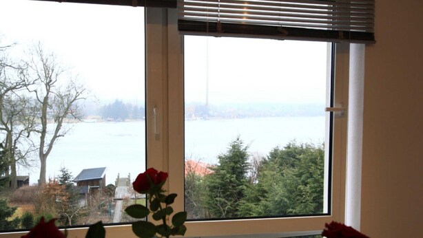 Una ventana con vista a un cuerpo de agua y árboles.