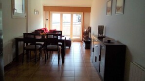 A spacious living area with a dining table, chairs, a sofa, and a television.