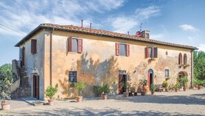 A rustic building with multiple windows and doors, surrounded by gravel and potted plants. - Beautiful home in Reggello FI (Reggello FI)