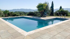 A rectangular swimming pool with a tiled deck, surrounded by a metal fence, and a view of mountains in the background. - Beautiful home in Reggello FI (Reggello FI)