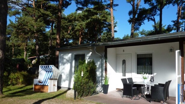 Un petit bâtiment d’un seul étage doté d’un patio aménagé avec du mobilier d’extérieur et une petite table.