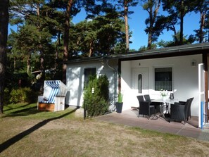 Un petit bâtiment d’un seul étage doté d’un patio aménagé avec du mobilier d’extérieur et une petite table.