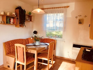 Un coin repas accueillant avec une table et des chaises en bois, une plante en pot et une fenêtre donnant sur l’extérieur.