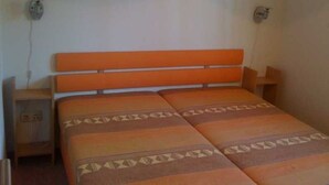 Une pièce comprenant un lit, une table de chevet et un luminaire fixé au mur.