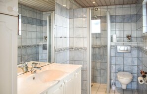 A bathroom with a sink, mirror, shower, toilet, and tiled walls. - Lovely home in Knebel with house sea view (Knebel)