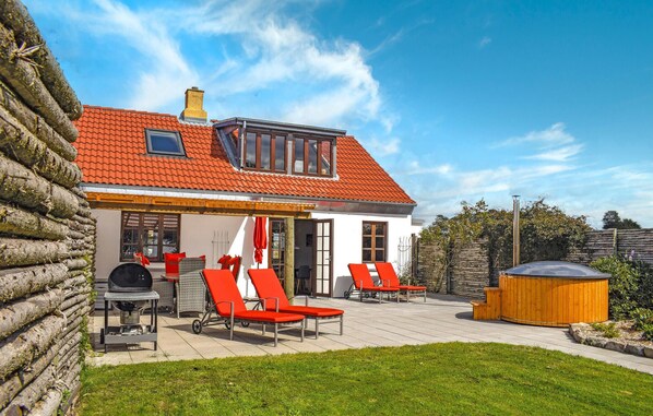 A house with a red tiled roof, a chimney, and a patio with red chairs and a barbecue grill. - Lovely home in Knebel with house sea view (Knebel)