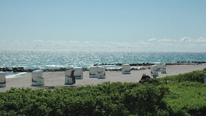 Una spiaggia con sedie a sdraio bianche e un litorale roccioso.