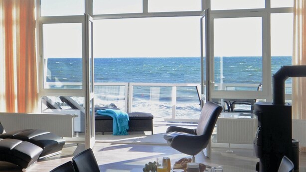 Una stanza con un'ampia finestra vista mare, un tavolo imbandito per la colazione e una sedia.
