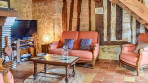 Uma sala de estar acolhedora com parede de pedra, teto de madeira e uma televisão sobre um suporte de madeira.