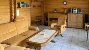A cozy log cabin interior with a sofa, armchair, and a coffee table. - Ferienhaus 7 in Thalfang (Thalfang)