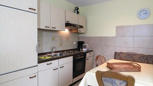 A compact kitchen with a stove, sink, and a clock on the wall. - Ferienhaus 7 in Thalfang (Thalfang)