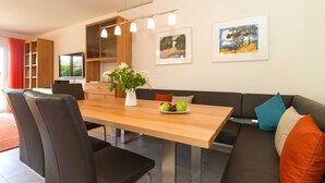 Un espai de viure modern amb taula de dinar, sofà, cadires i obra d'art a les parets.