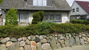 Ein zweistöckiges Haus mit einer Steinsäule davor, einem Ziegeldach und einem Schild mit der Aufschrift 'Kaan Roni'.