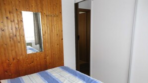 Ein Schlafzimmer mit einer Holzwand, einem Bett mit gestreifter Bettdecke, einem Spiegel und einem Kleiderschrank.