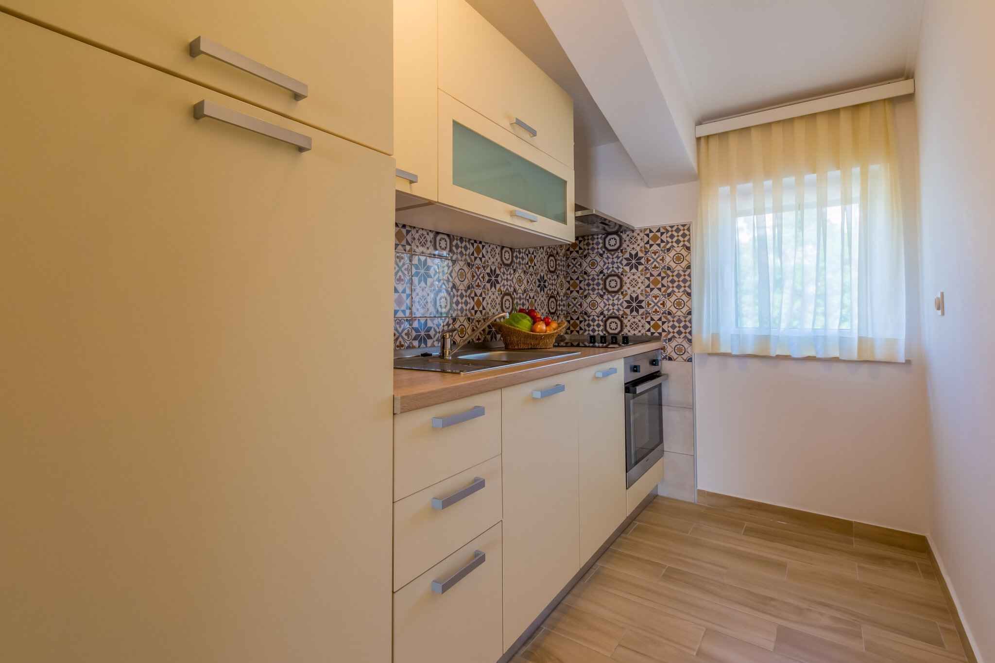 A compact kitchen with light-colored cabinets, a microwave, and a tiled backsplash.