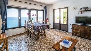 A living room with a dining table, chairs, a TV, and a view of the sea. - Gorgeous apartment in Jávea with swimming pool (Jávea)