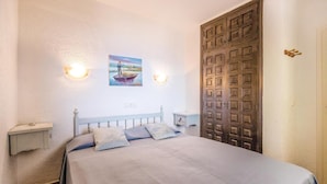 A bedroom with a bed, a nightstand, a wall-mounted lamp, and a door. - Gorgeous apartment in Jávea with swimming pool (Jávea)